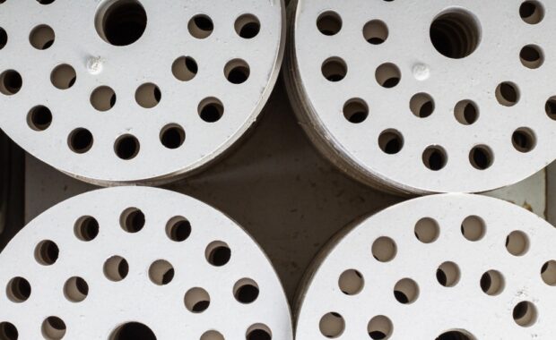 Close-up of four white ceramic discs sitting close together on a table. Each disc features several holes.